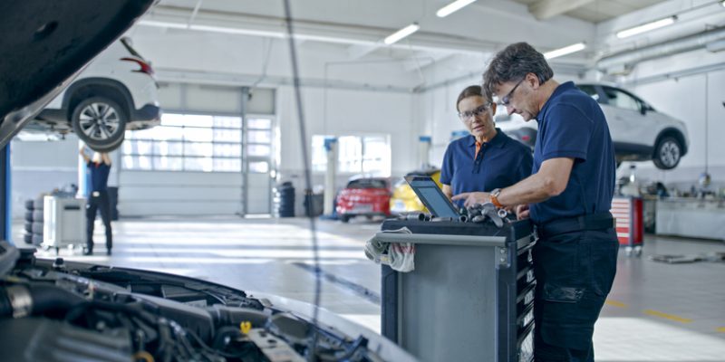 Manager And Mechanic Evaluating The Car Engine Using Laptop At Workshop - Mspark Auto service technicians