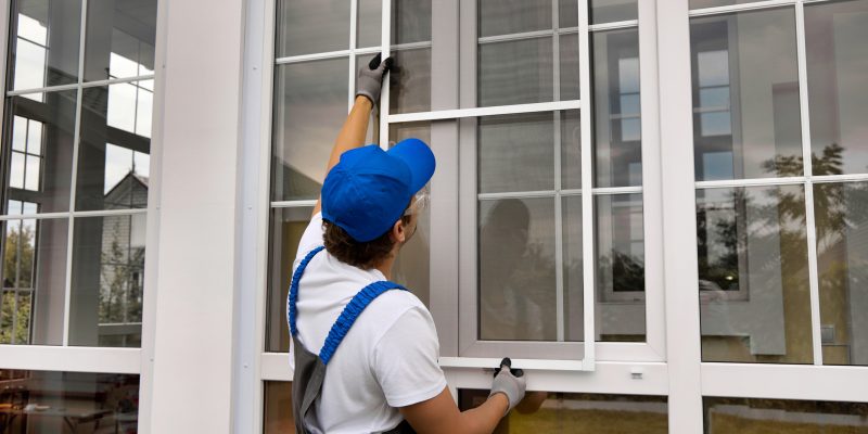 Installation of a mosquito net on a large window outside a modern building - Mspark home services marketing window replacement
