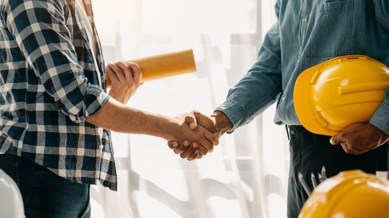 Construction team shake hands greeting start new project plan behind yellow helmet on desk in office center to consults about their building project - Mspark